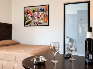 A hotel room with a bed, a table with two wine glasses and a bottle, and a colorful abstract painting on the wall. - Calacoto Queen Suite Sleeps 4 Zona Sur Wi-fi (La Paz)