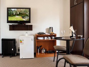 A hotel room with a television, a mini-fridge, a dining table with chairs, a cabinet, and a radiator. - Calacoto Queen Suite Sleeps 4 Zona Sur Wi-fi (La Paz)