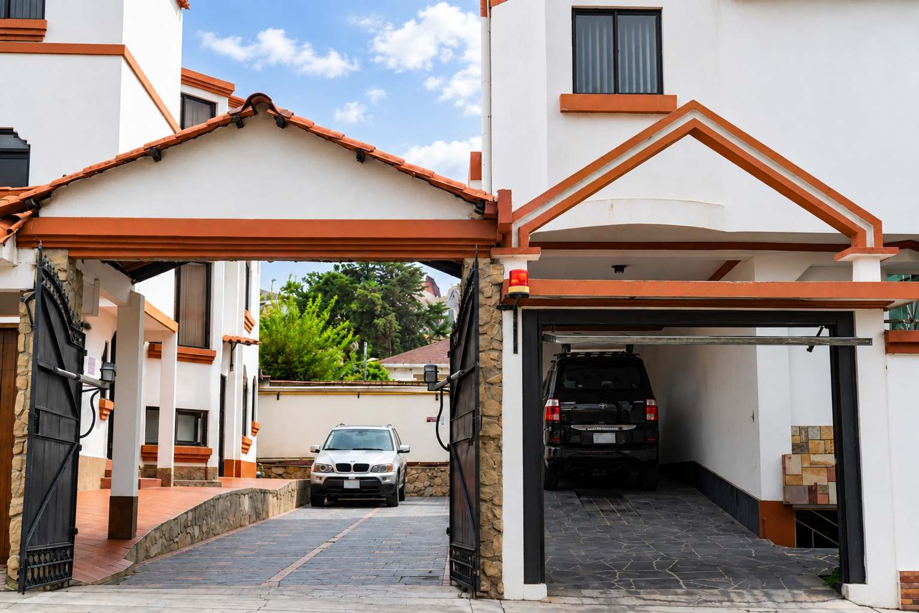 A gated driveway leading to a garage with a vehicle parked inside.