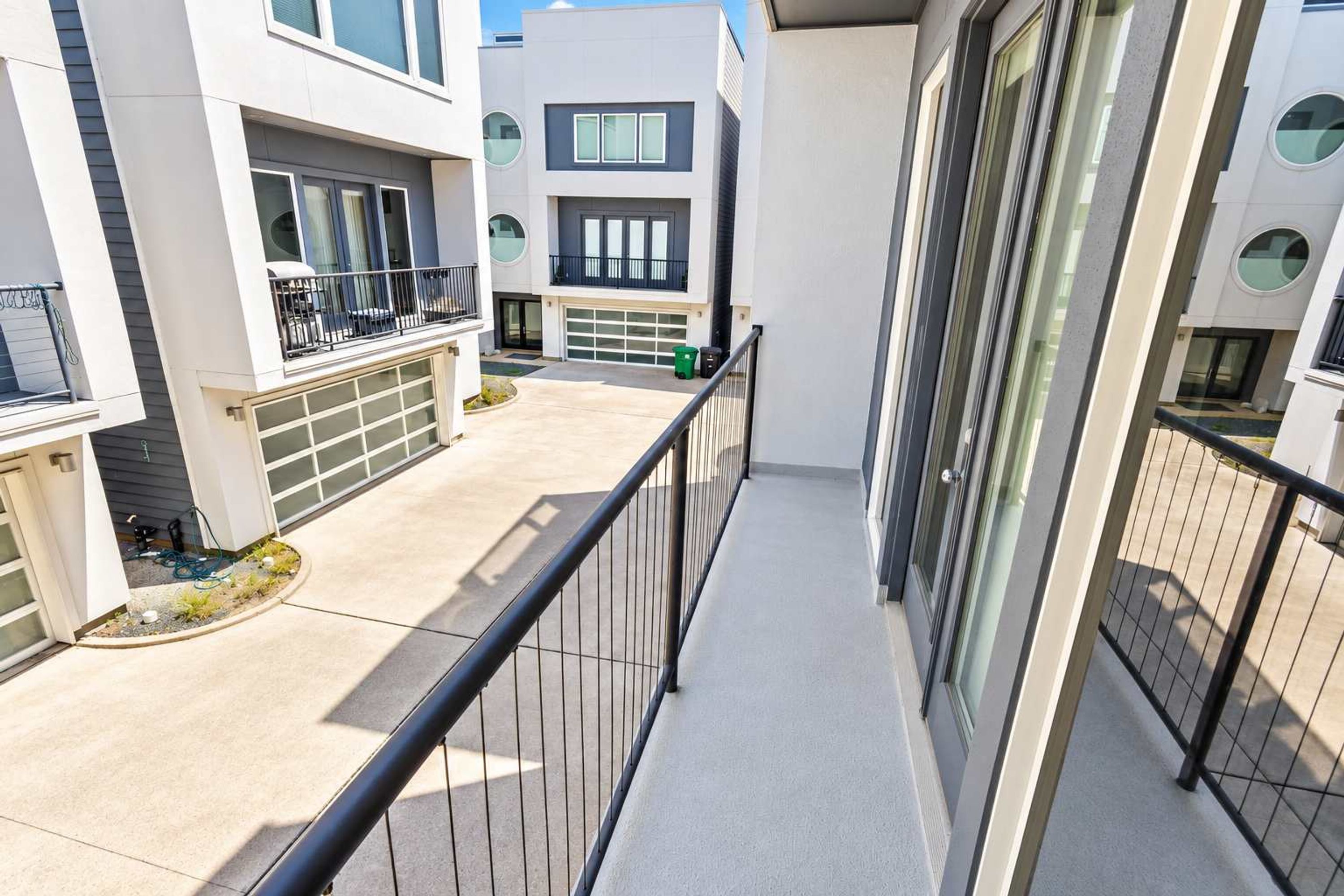 Um edifício residencial moderno com varanda, garagem e área de jardim bem cuidada.