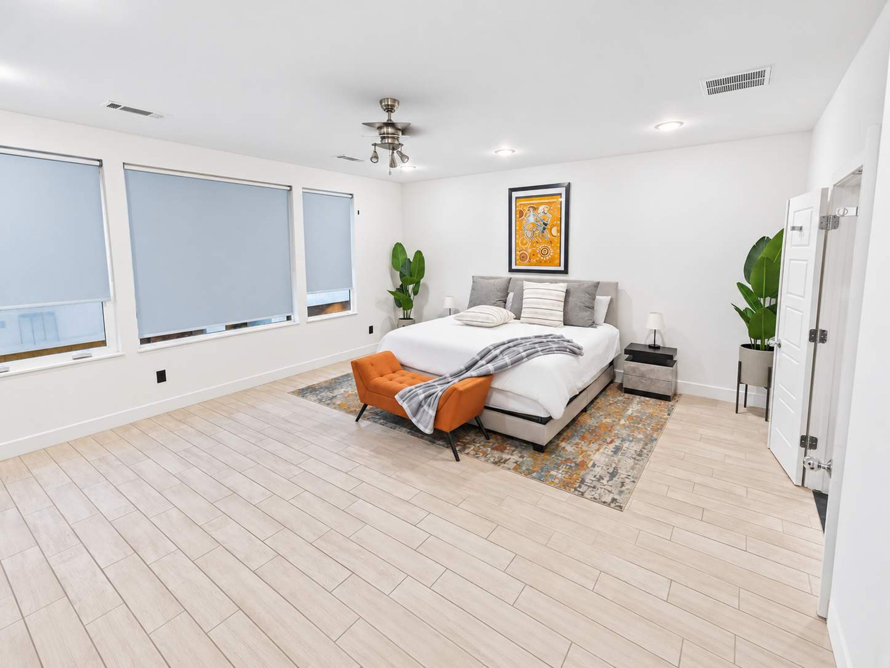 A modern bedroom with a bed, a chair, a nightstand, and a large window.