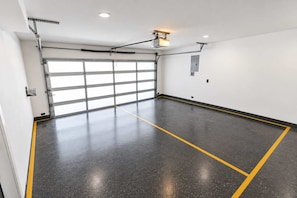 Un garaje limpio y vacío, con piso de concreto y una puerta grande.