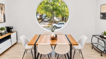 Un coin repas doté d’une fenêtre ronde donnant sur une rue bordée d’arbres.