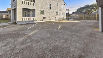 A building with a brick facade, a large parking lot, and a fenced area.