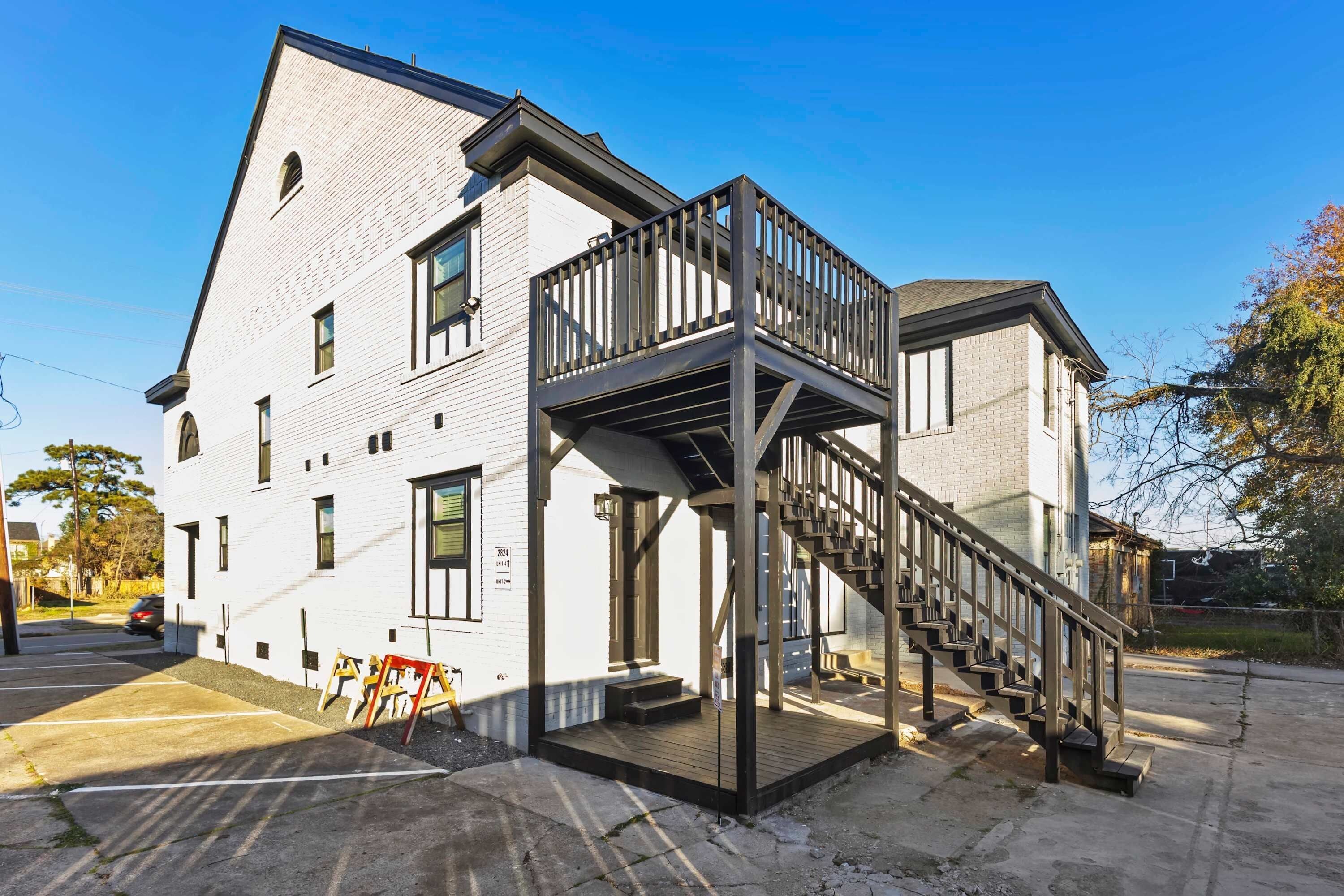 A two-story building with a balcony and a staircase leading to the upper floor.