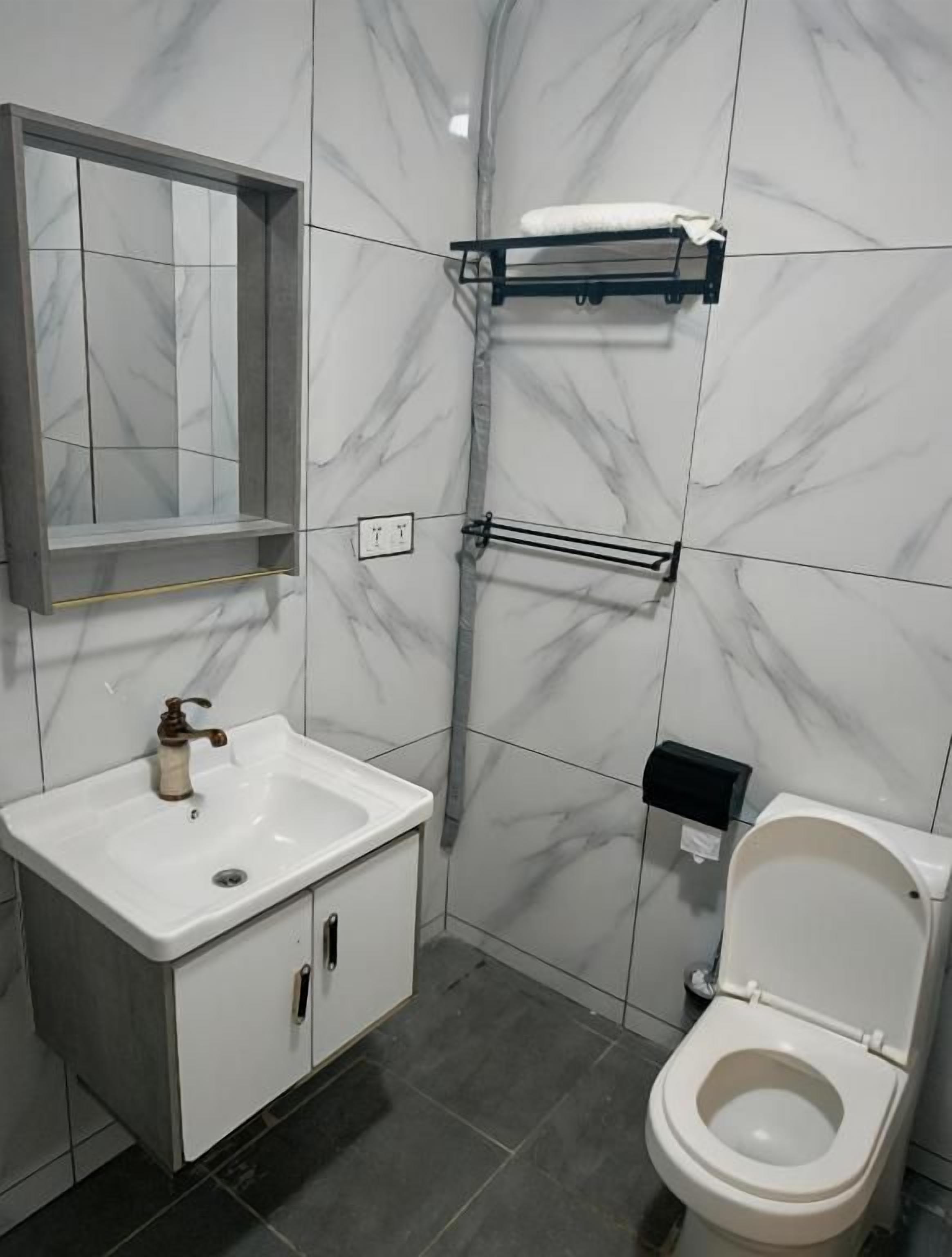 Un baño con un lavamanos blanco, un inodoro y un espejo.