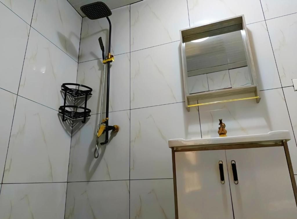 Une salle de bain avec une douche, un lavabo et un meuble de rangement.