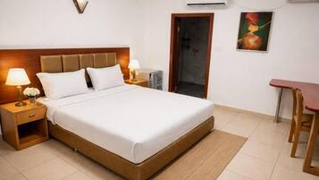 Een hotelkamer met een bed, nachtkastjes, een bureau en een airconditioner.