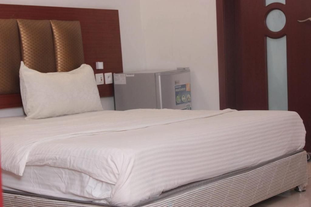 Ein Hotelzimmer mit einem Bett, einem kleinen Kühlschrank und einem Holzkopfstück.