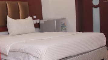 Ein Hotelzimmer mit einem Bett, einem kleinen Kühlschrank und einem Holzkopfstück.