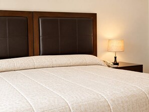 Un lit avec une tête de lit, une lampe de chevet et un téléphone sur une table de chevet.