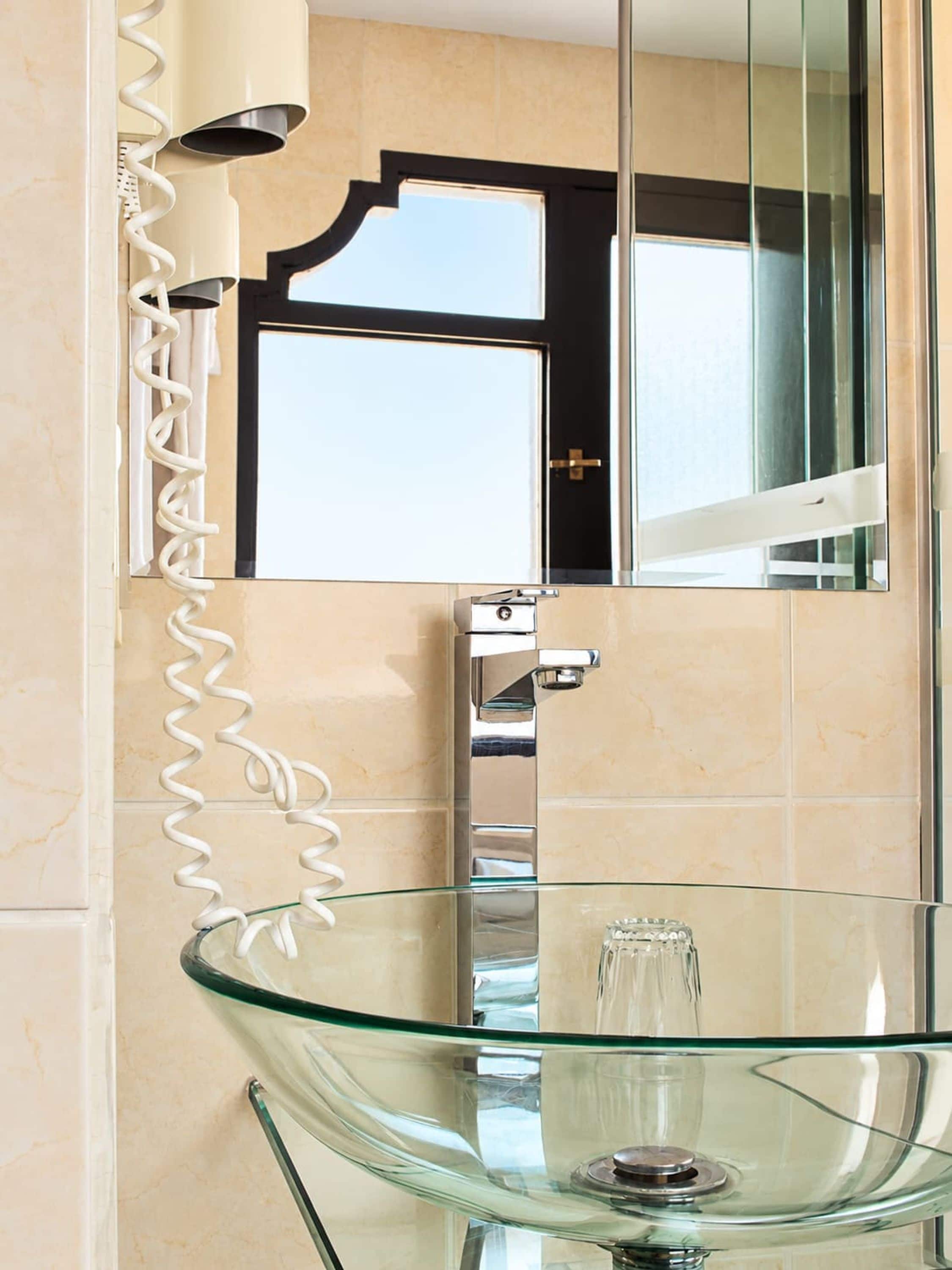 A bathroom with a glass vessel sink, a chrome faucet, and a wall-mounted mirror.