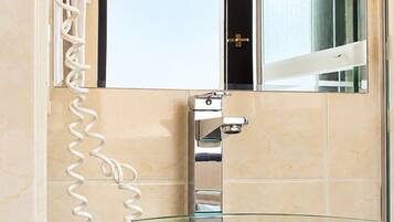 A bathroom with a glass vessel sink, a chrome faucet, and a wall-mounted mirror.
