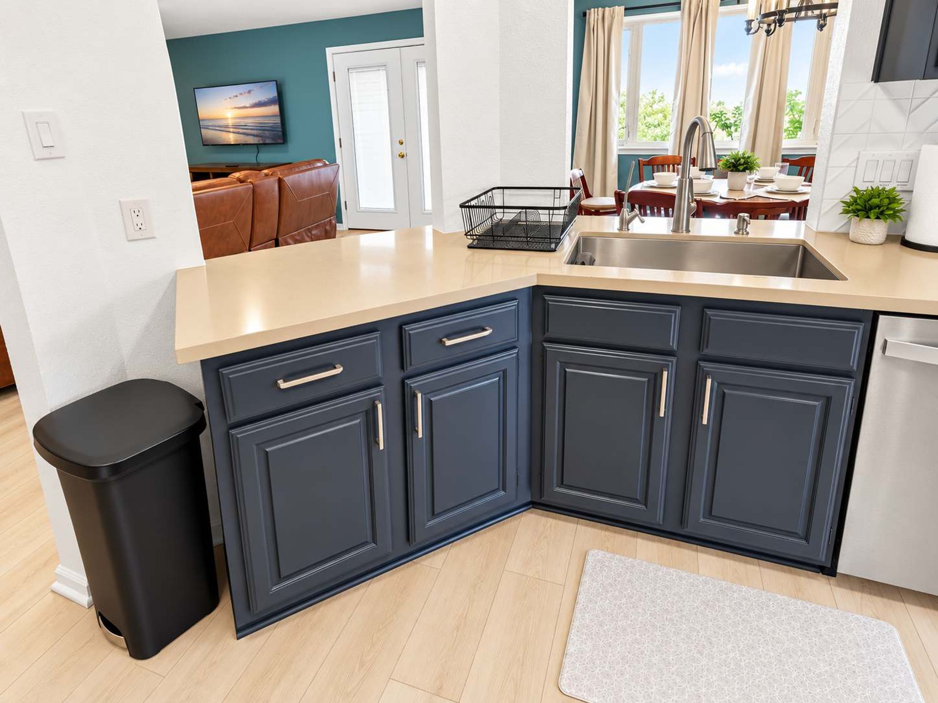 A modern kitchen with dark blue cabinets, a stainless steel sink, and a countertop.