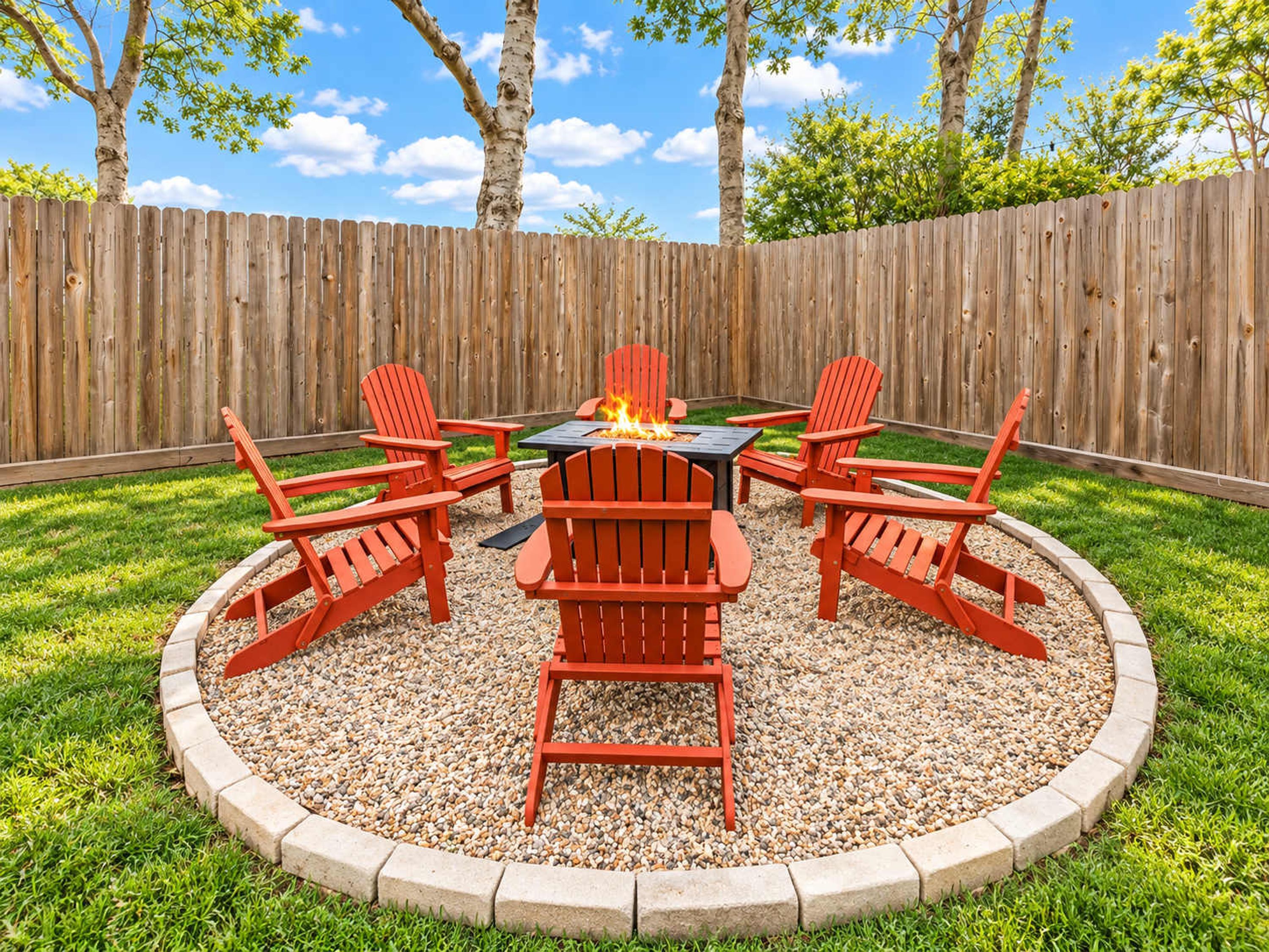 A circular outdoor seating area with a fire pit and red chairs.