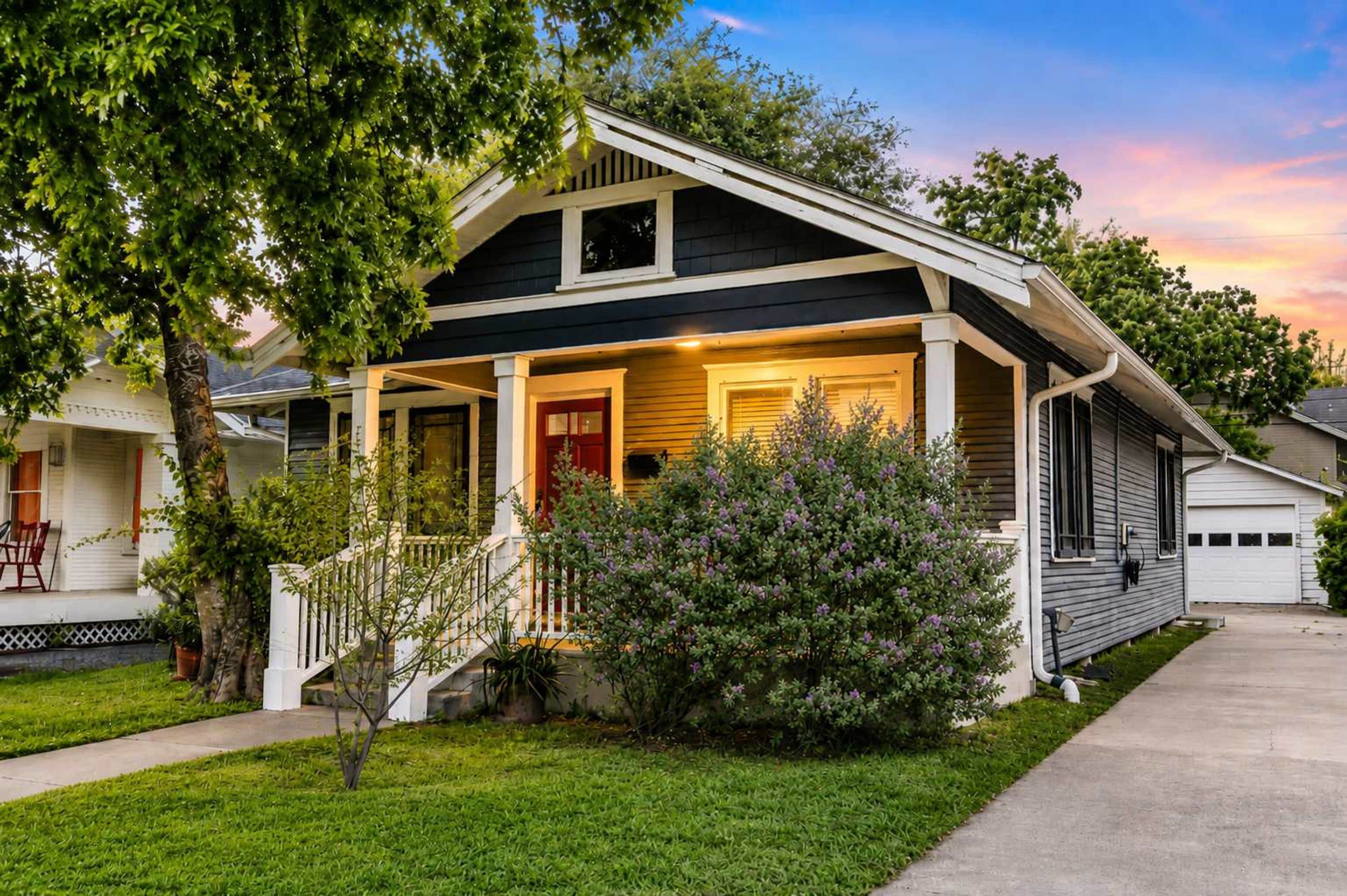 A two-story house with a front porch, a garage, and a well-maintained lawn.