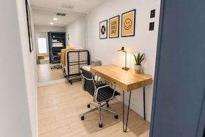 Un espace de bureau moderne avec un bureau en bois, une chaise de bureau noire, un lampadaire et une plante en pot.