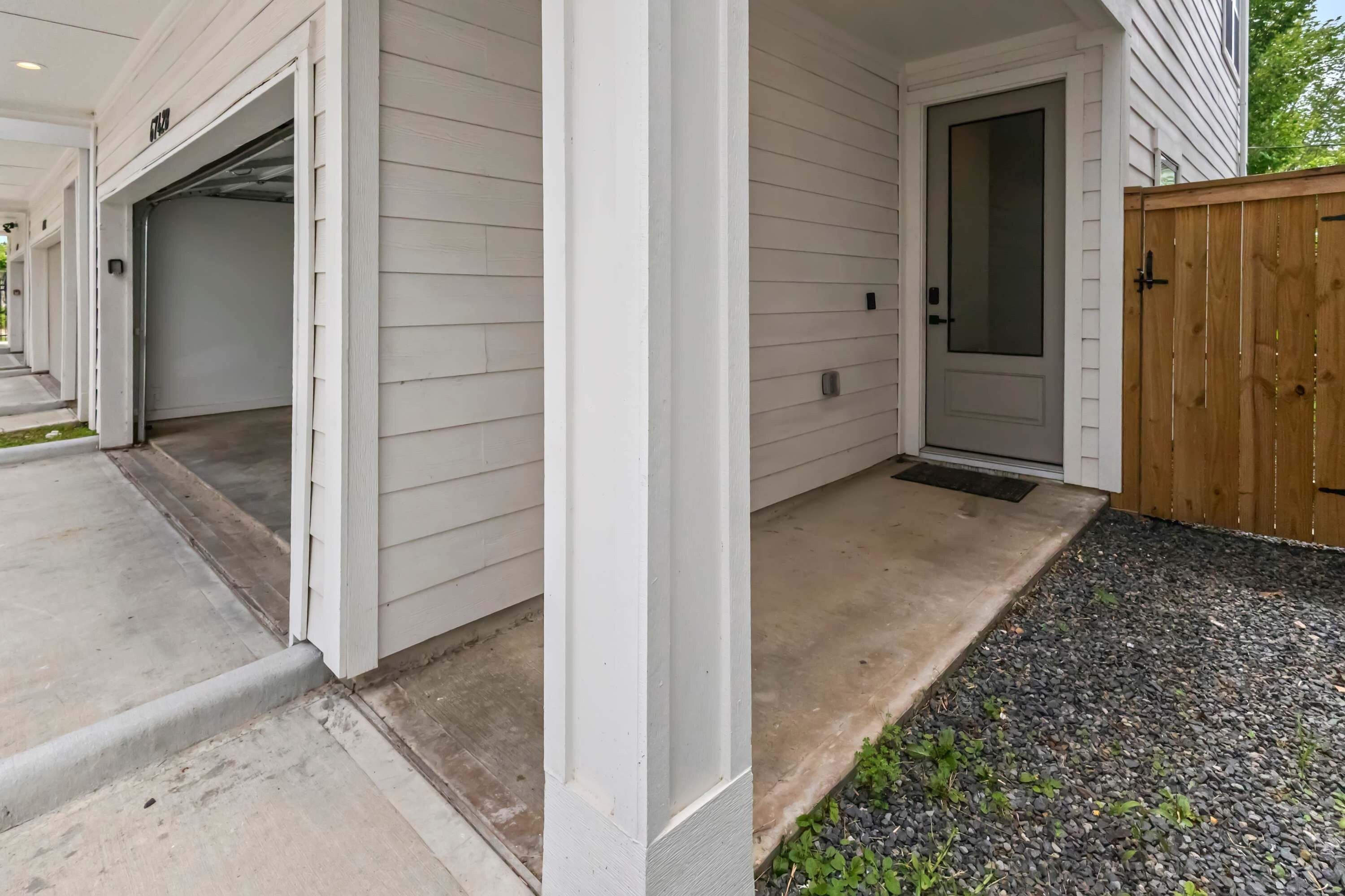 A residential entryway with a garage door, a front door, and a wooden fence.