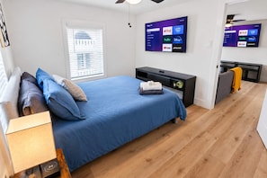 A bedroom with a bed, a TV mounted on the wall, and a window with blinds. - Historic Loft - 1 Medcenter NRG DT Fifa (Houston)