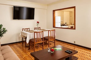 A hotel room with a dining table, chairs, a television, a mirror, and a sofa. - Calacoto Secret Garden 3BR Zona Sur Parking (La Paz)