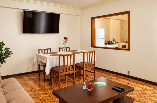 A hotel room with a dining table, chairs, a television, a mirror, and a sofa. - Calacoto Secret Garden 3BR Zona Sur Parking (La Paz)