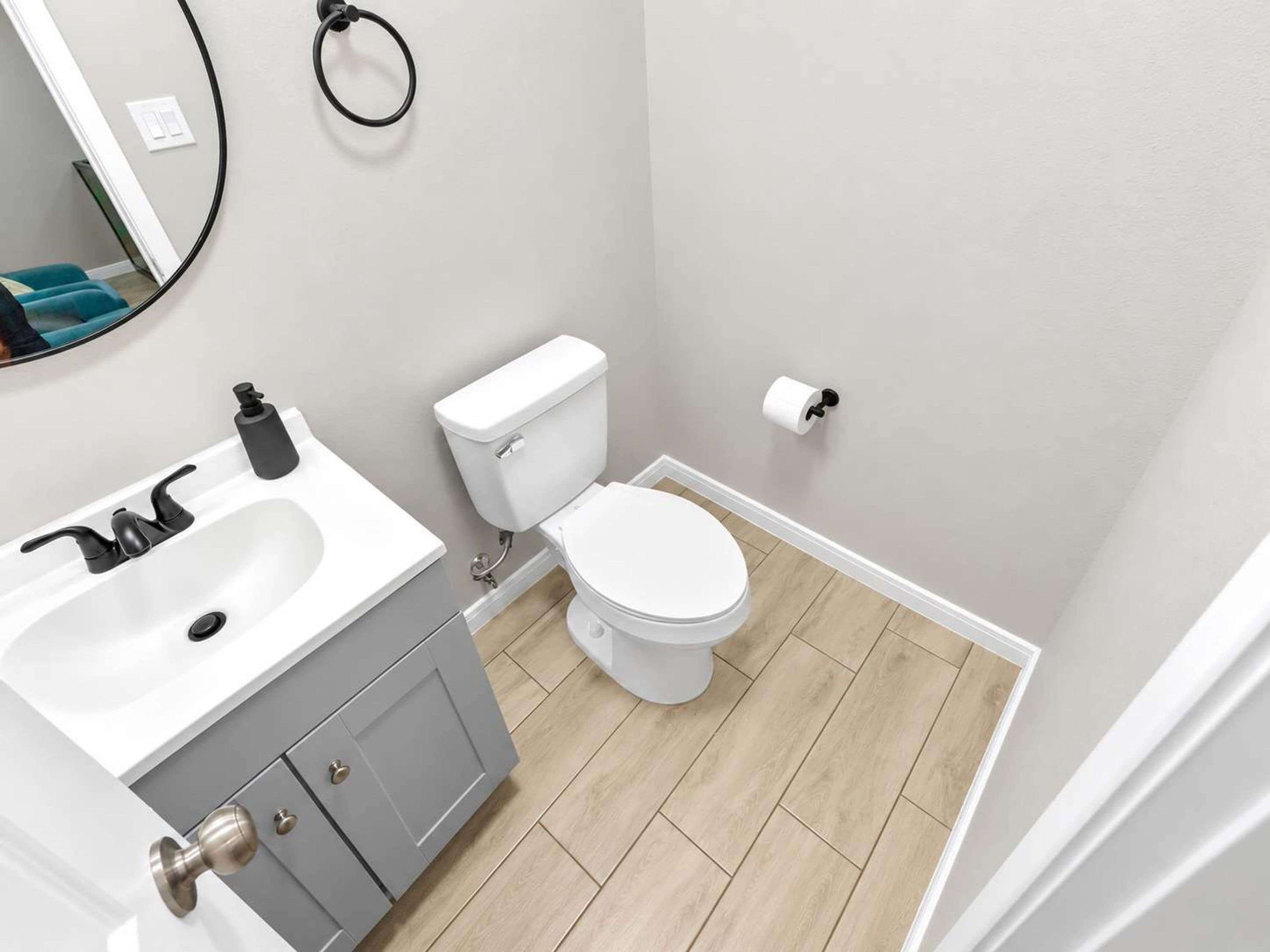 Un baño con lavamanos blanco, inodoro y espejo.