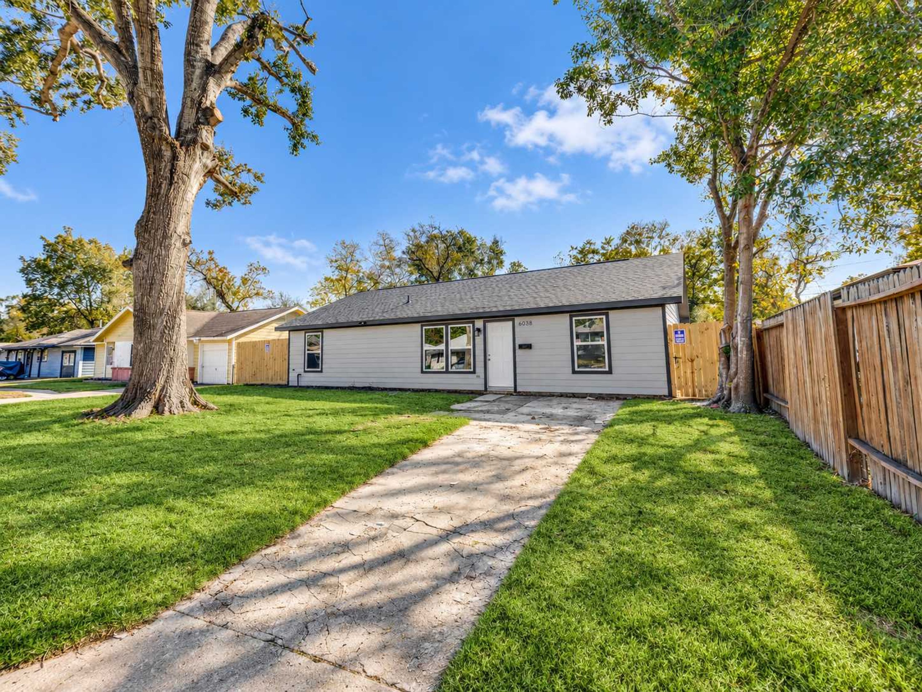 A single-story house with a front yard, a driveway, and a wooden fence.