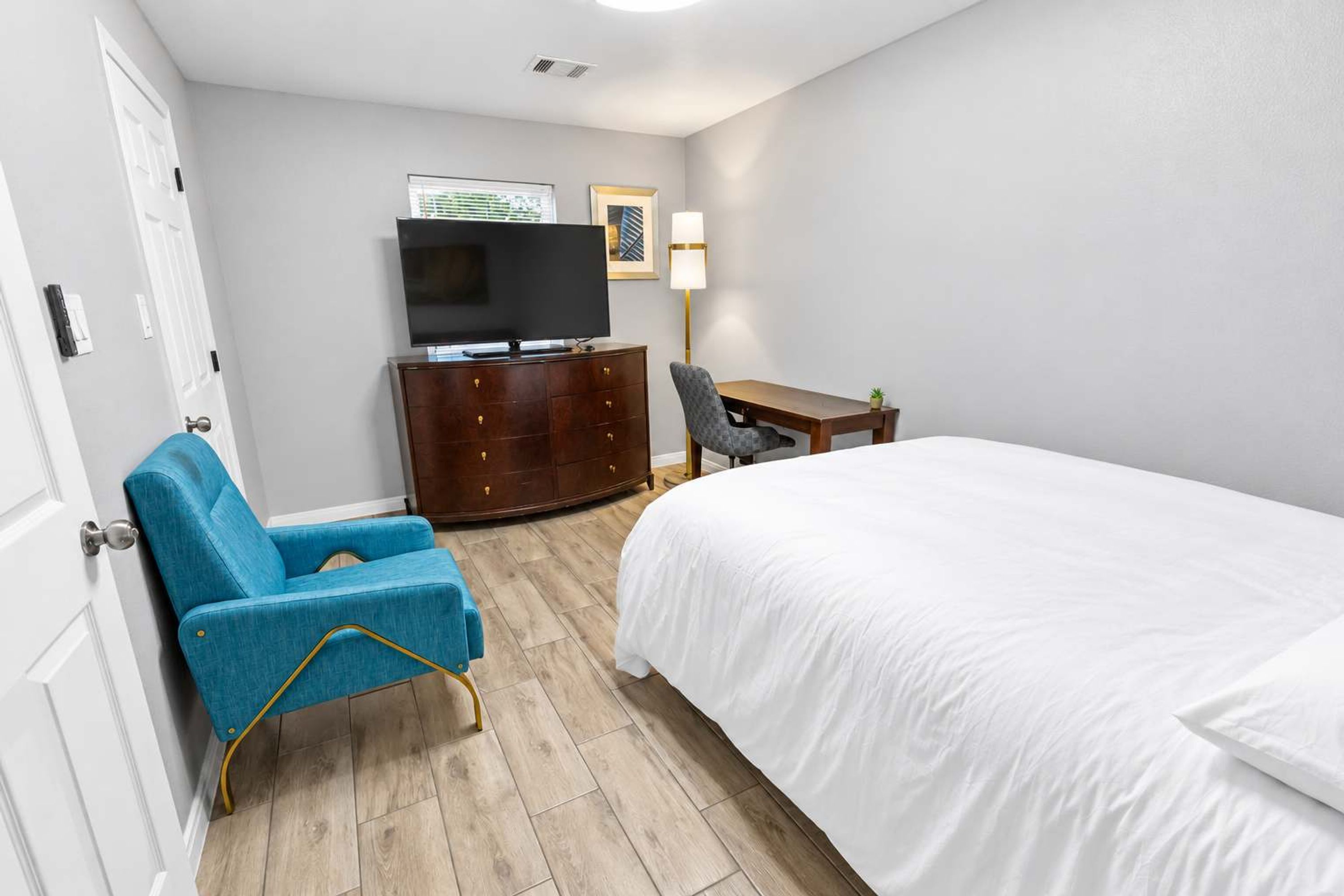 Una habitación de hotel con cama, televisión, escritorio, silla y cómoda.