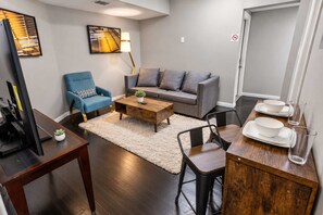 Una sala de estar moderna con sofá, sillón, mesa de centro y comedor con sillas y mesa.