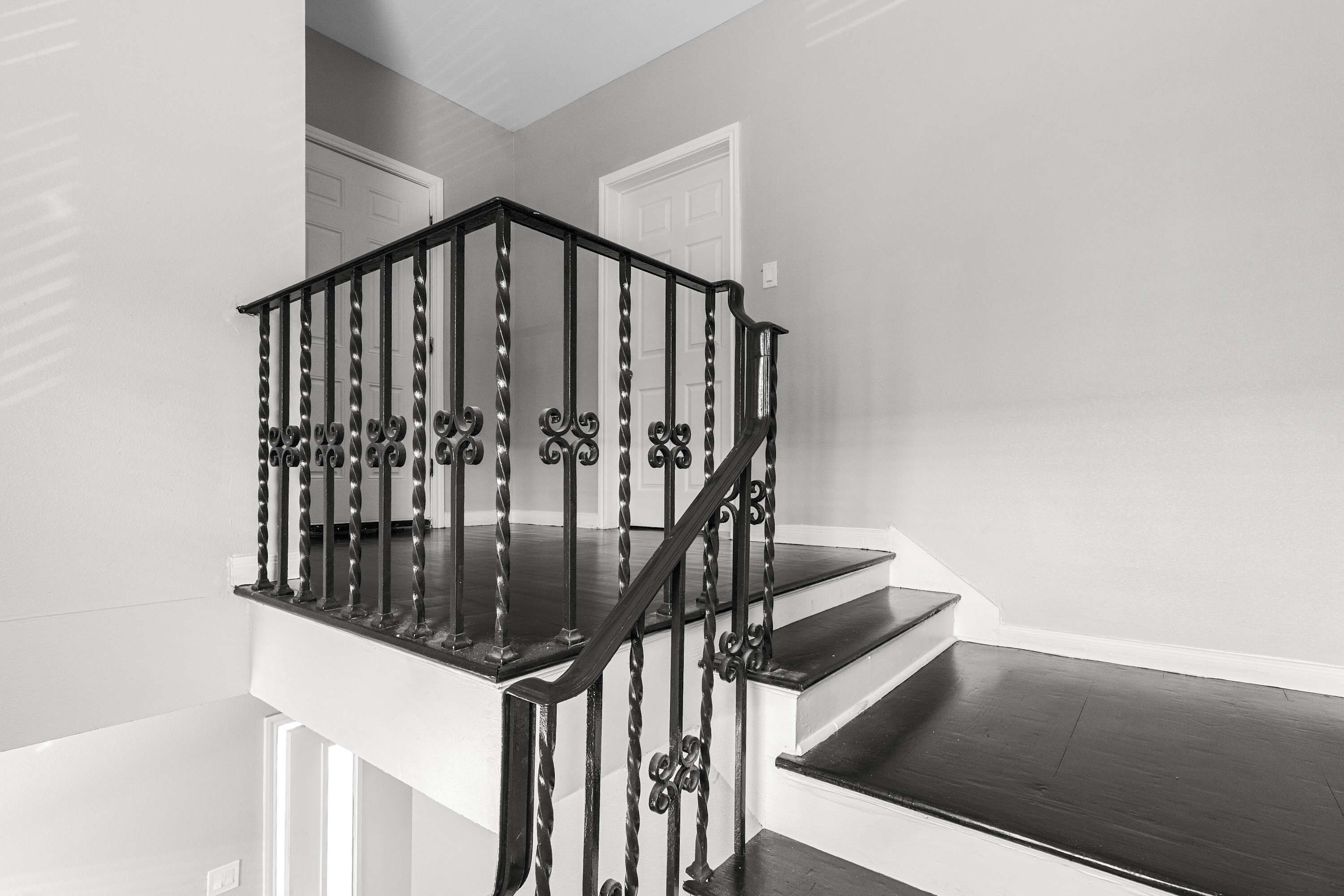 A black metal staircase with a handrail and a landing.