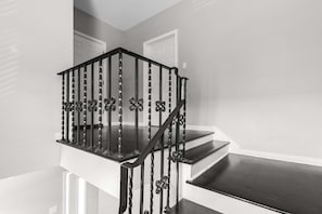 Una escalera con barandilla de metal negro y peldaños de madera.