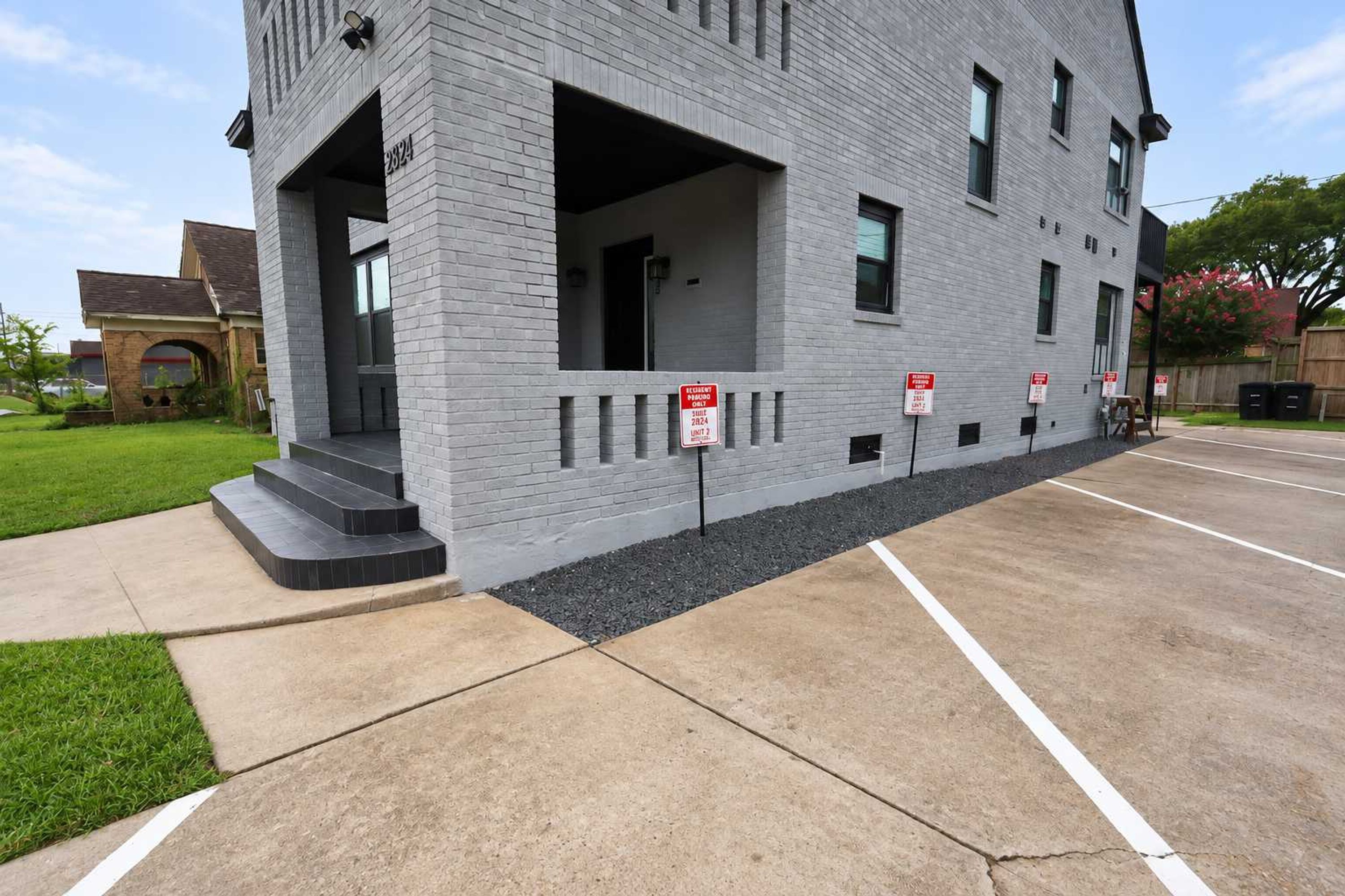 A modern building with a brick facade, multiple windows, and a parking lot.