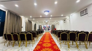 A conference room with rows of chairs, a red carpet, and a chandelier. - ZINGS HOTEL AND RESTRUANT (Etawah)