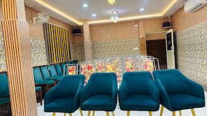 A room with teal chairs, a patterned wall, and a ceiling fan. - ZINGS HOTEL AND RESTRUANT (Etawah)