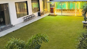 A courtyard with artificial grass, outdoor seating, and a bar area with string lights.