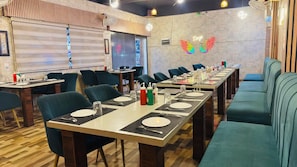 A restaurant with multiple tables and chairs, a neon sign, and a wooden floor. - ZINGS HOTEL AND RESTRUANT (Etawah)