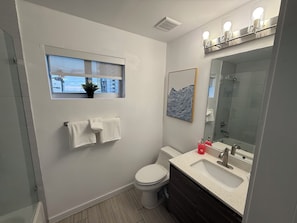 A modern bathroom with a toilet, sink, and a window with a view. - Midtown Wynwood 2 bedroom condo w/h free parking (Miami)