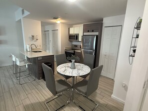 A modern kitchen with a central island, stainless steel appliances, and a dining area with a marble table. - Midtown Wynwood 2 bedroom condo w/h free parking (Miami)
