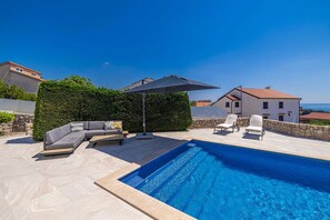 A swimming pool with a sun lounger and a sofa, surrounded by a stone wall and a hedge. - Villa SIA With Private Pool (Krk)