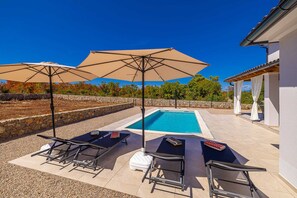 Ein Poolbereich mit Liegestühlen, Sonnenschirmen und einem Schwimmbecken.