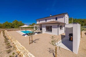 Ein zweigeschossiges Haus mit Swimmingpool, Sitzgelegenheit im Freien und Garten.