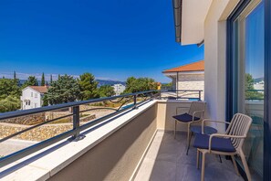 A balcony with a view of a coastal landscape, a stone wall, and a small table with chairs. - Villa Adria Moments With Private Pool (Krk)