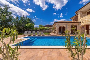 A swimming pool with lounge chairs, surrounded by stone buildings and greenery. - Holiday House Casa DI Bronzo With Private Pool (Krk)