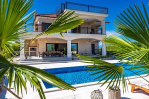 A two-story building with a swimming pool, outdoor seating, and a balcony. - Luxury Villa Glabrova With Pool Jacuzzi and Sauna (Dobrinj)