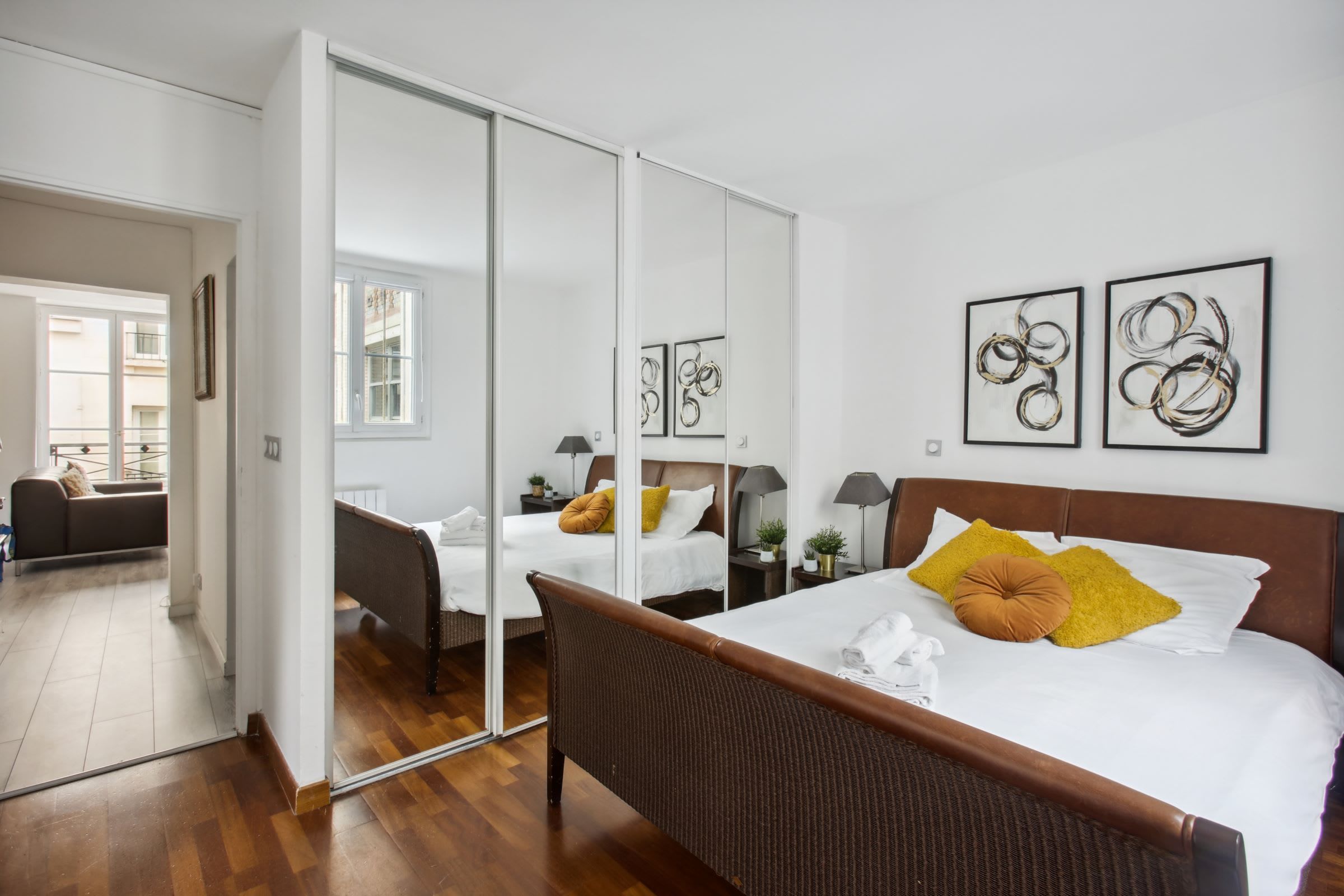 Una camera d'albergo con un letto grande, uno specchio e opere d'arte alle pareti.