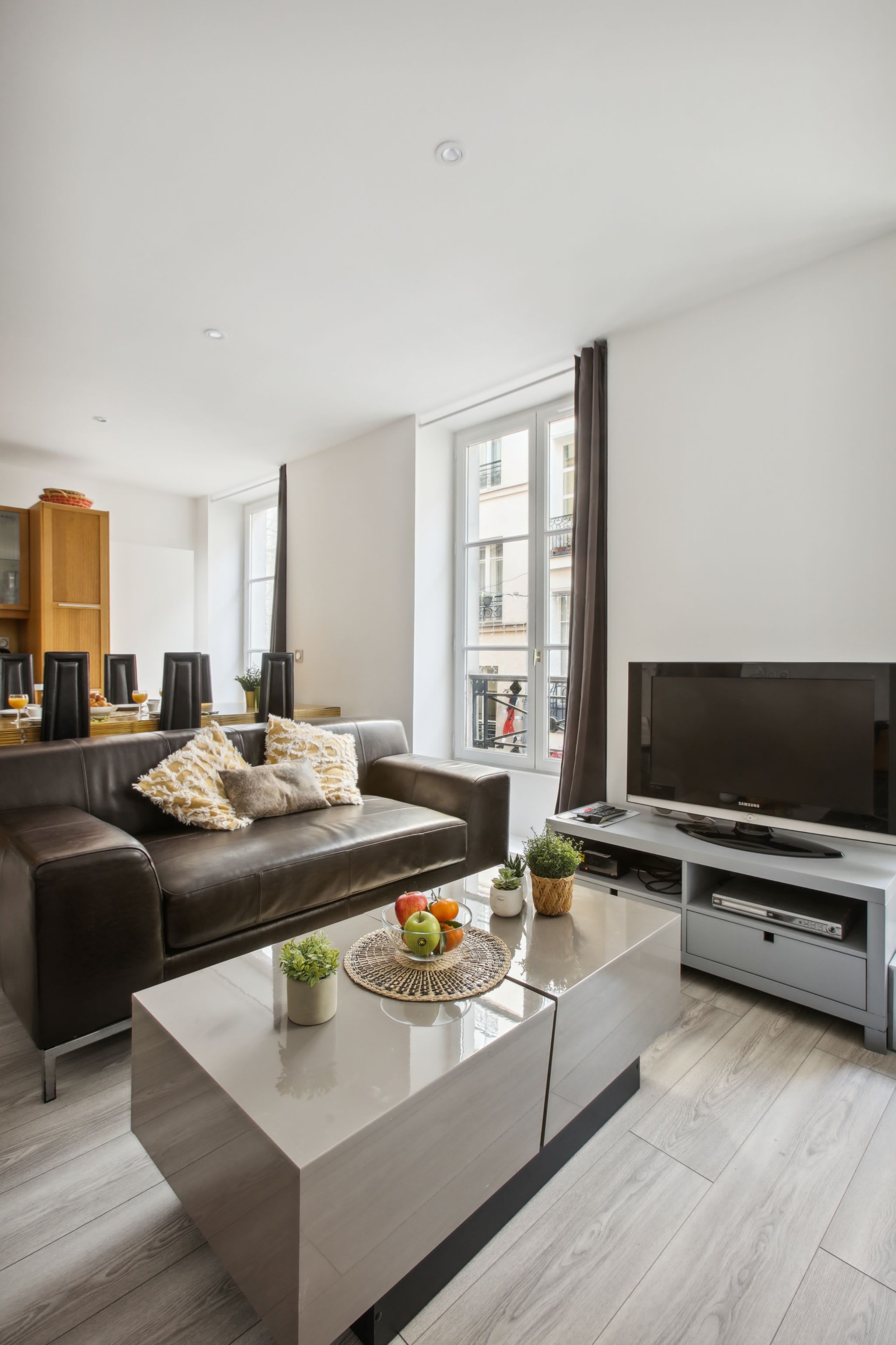 Een moderne woonkamer met een bruine leren bank, een glazen salontafel en een flatscreen televisie.