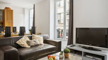 Een moderne woonkamer met een bruine leren bank, een glazen salontafel en een flatscreen televisie.