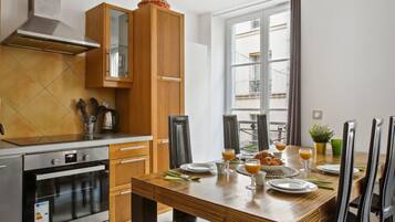 Eine moderne Küche mit Holzausbau, einem Esstisch für sechs Personen und einem großen Fenster, das für natürliches Licht sorgt.