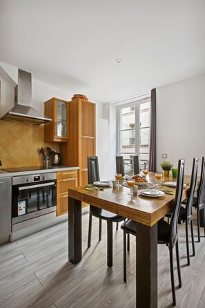 Een moderne keuken met houten kastjes, een eettafel gedekt voor zes personen, en een groot raam dat zorgt voor natuurlijk licht.