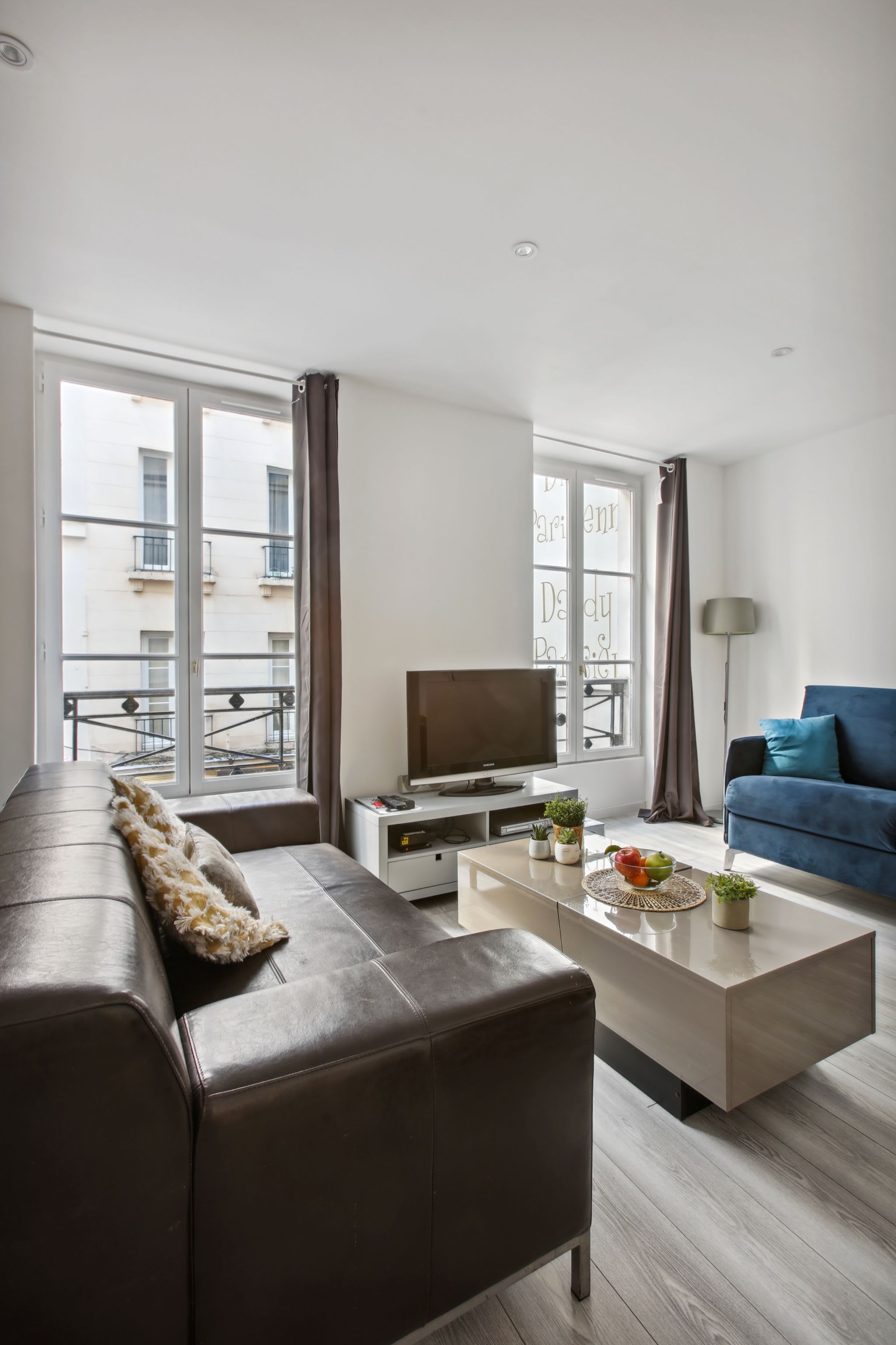 Een moderne woonkamer met een bank, salontafel, televisie en uitzicht op een balkon.